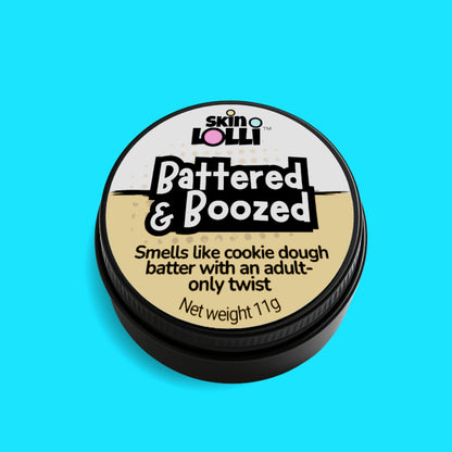 Tin of Skin Lolli 'Battered & Boozed' cookie dough swipe on scent on a aqua background